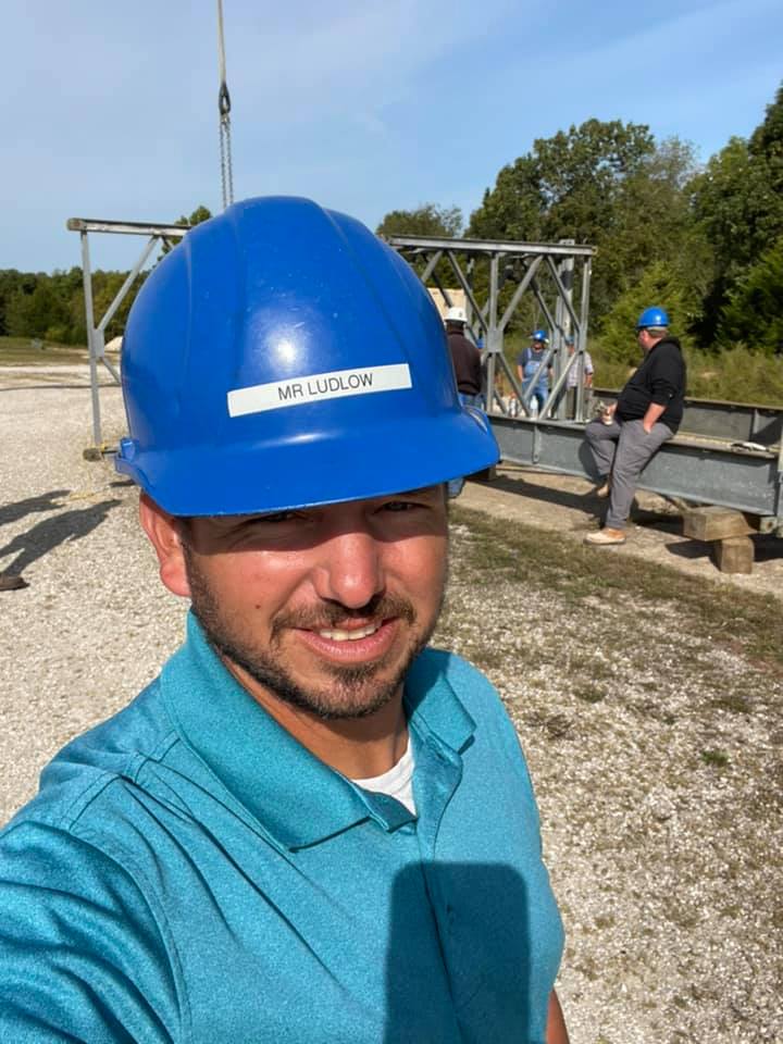 A man wearing a hard hat and a blue shirt taking a selfie pic
